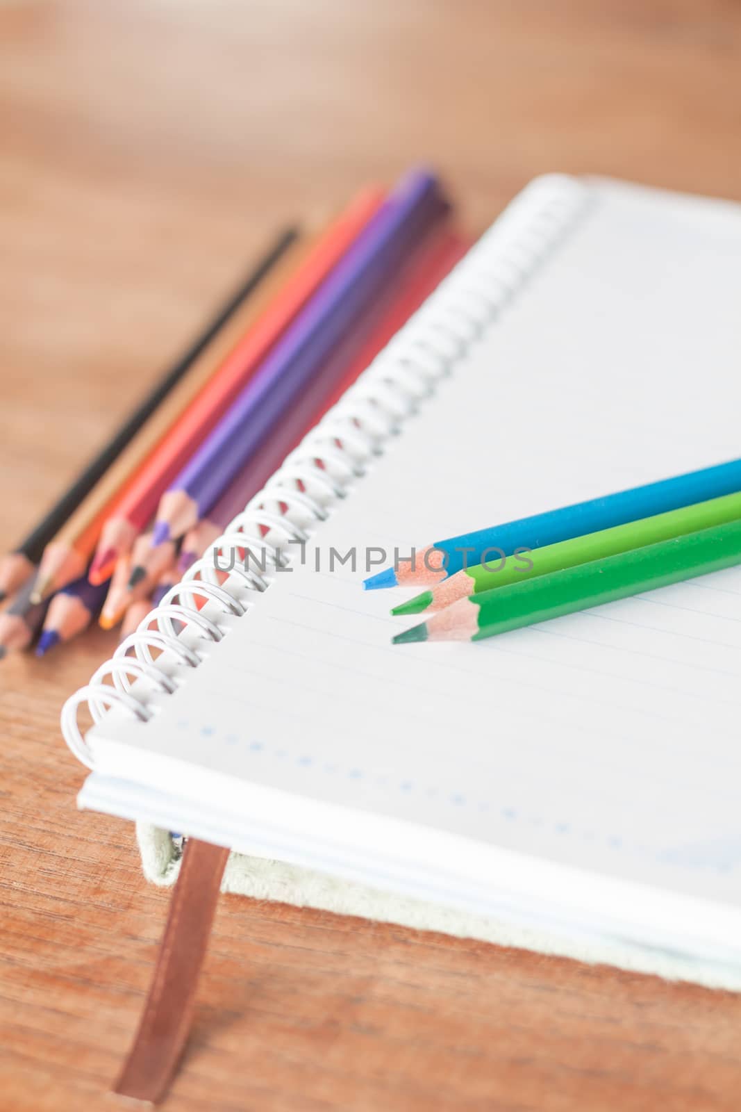 Colorful pencils on spiral notebook and green notebook, stock photo