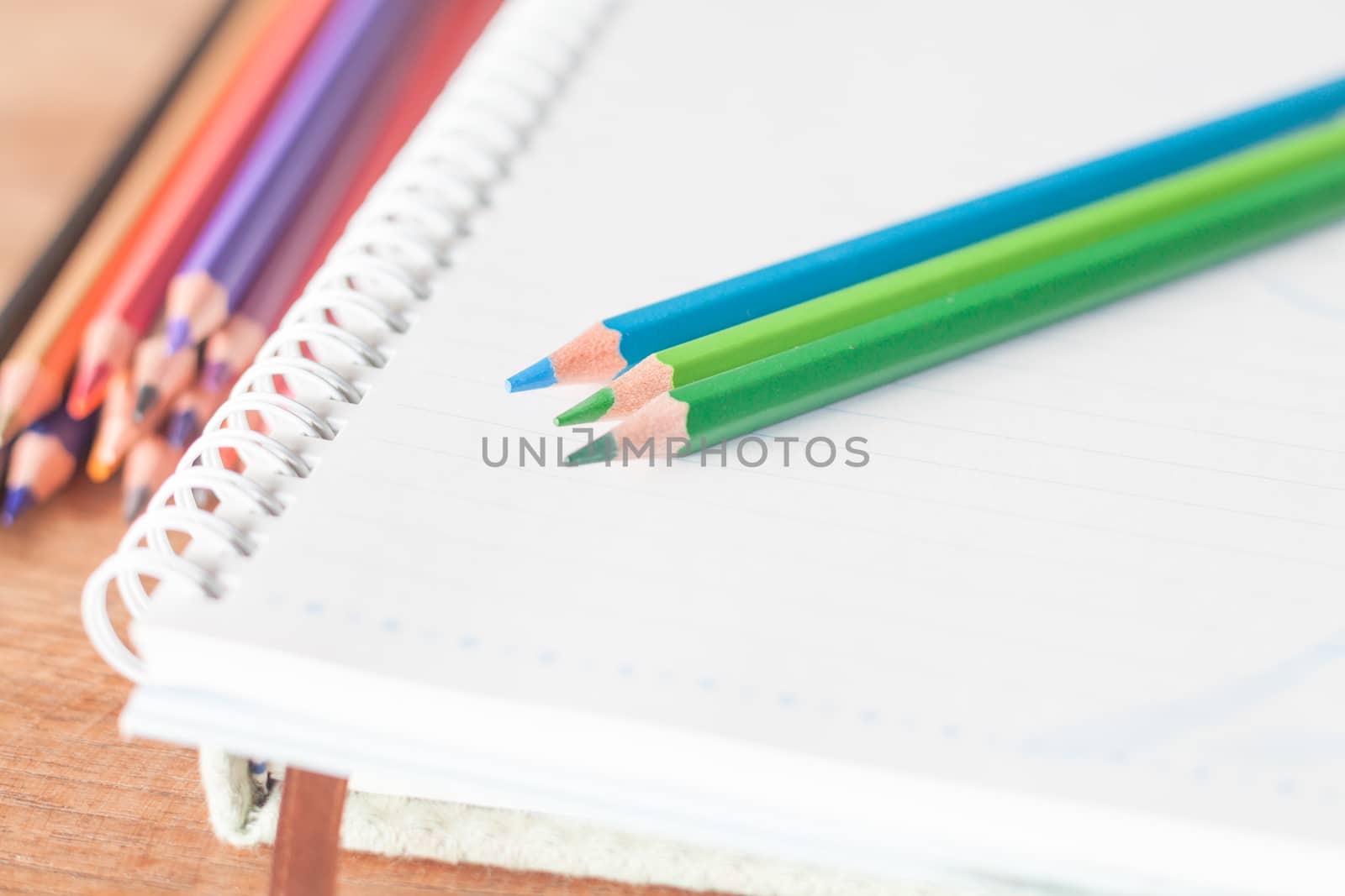 Closeup colorful pencils on spiral notebook and green notebook, stock photo
