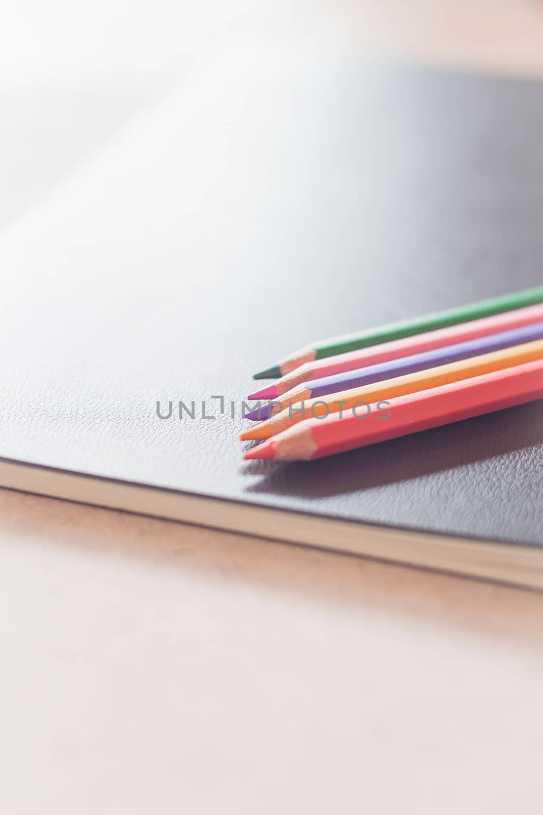 Colorful pencils on black notebook by punsayaporn
