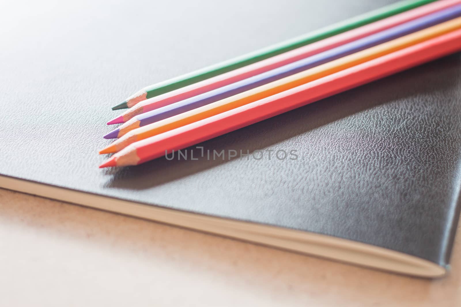 Closeup color pencils on black notebook, stock photo