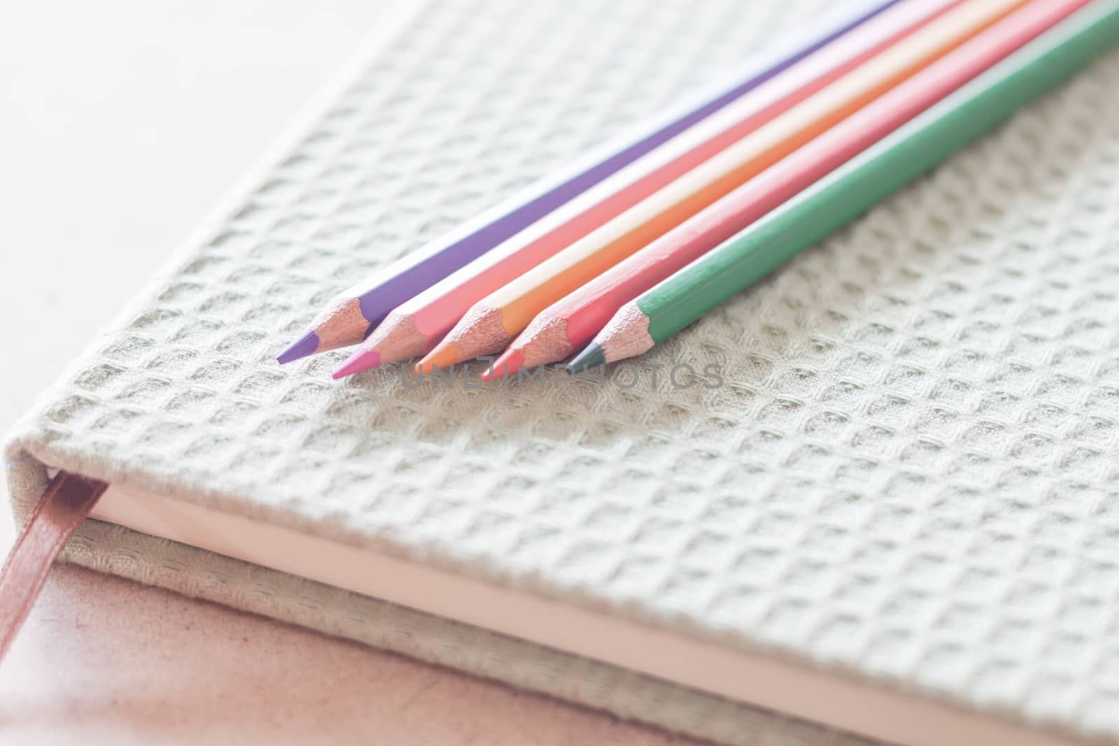 Closeup colorful pencils on green notebook by punsayaporn