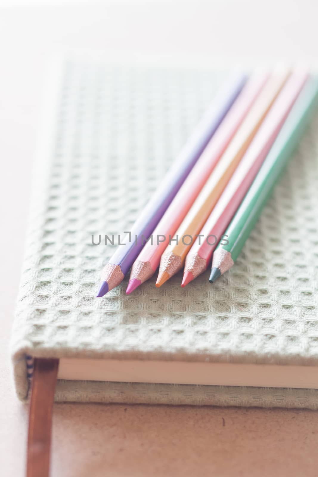 Closeup color pencils on green notebook by punsayaporn