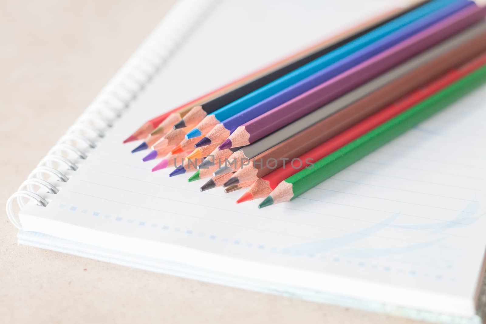 Closeup colorful pencil crayons on spiral notebook by punsayaporn