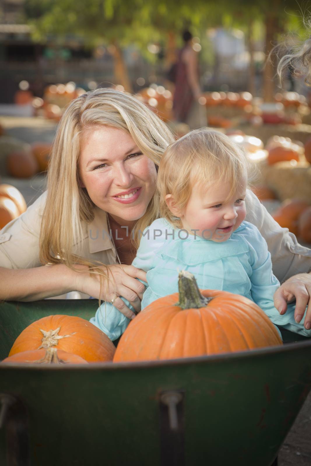 Adorable Young Mother and Daughter Enjoys a Day at the Pumpkin Patch.