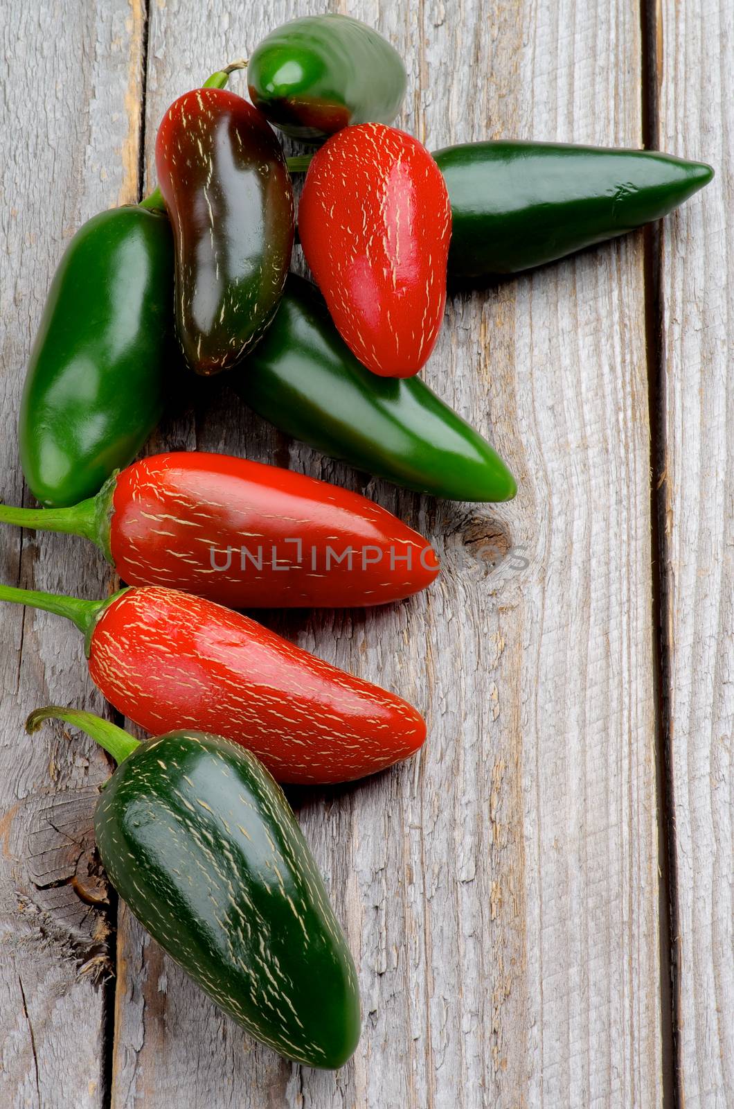 Stack of Red and Green Habanero and Jalapeño Chili Peppers isolated on Rustic Wooden background