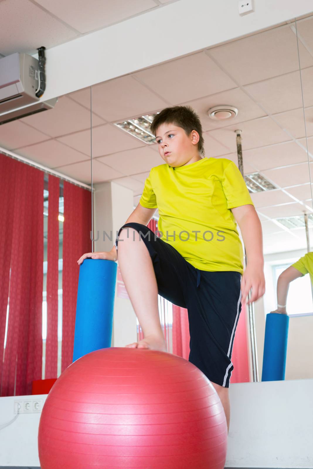 Boy does exercise with the ball in gym by olgavolodina