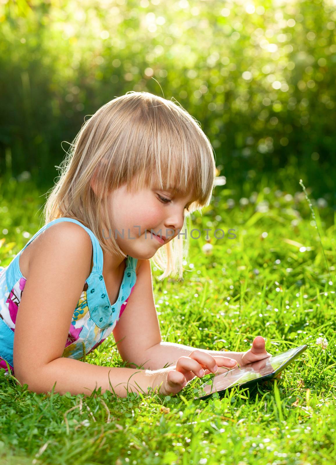 Little girl usng a touch pad in a summer garden