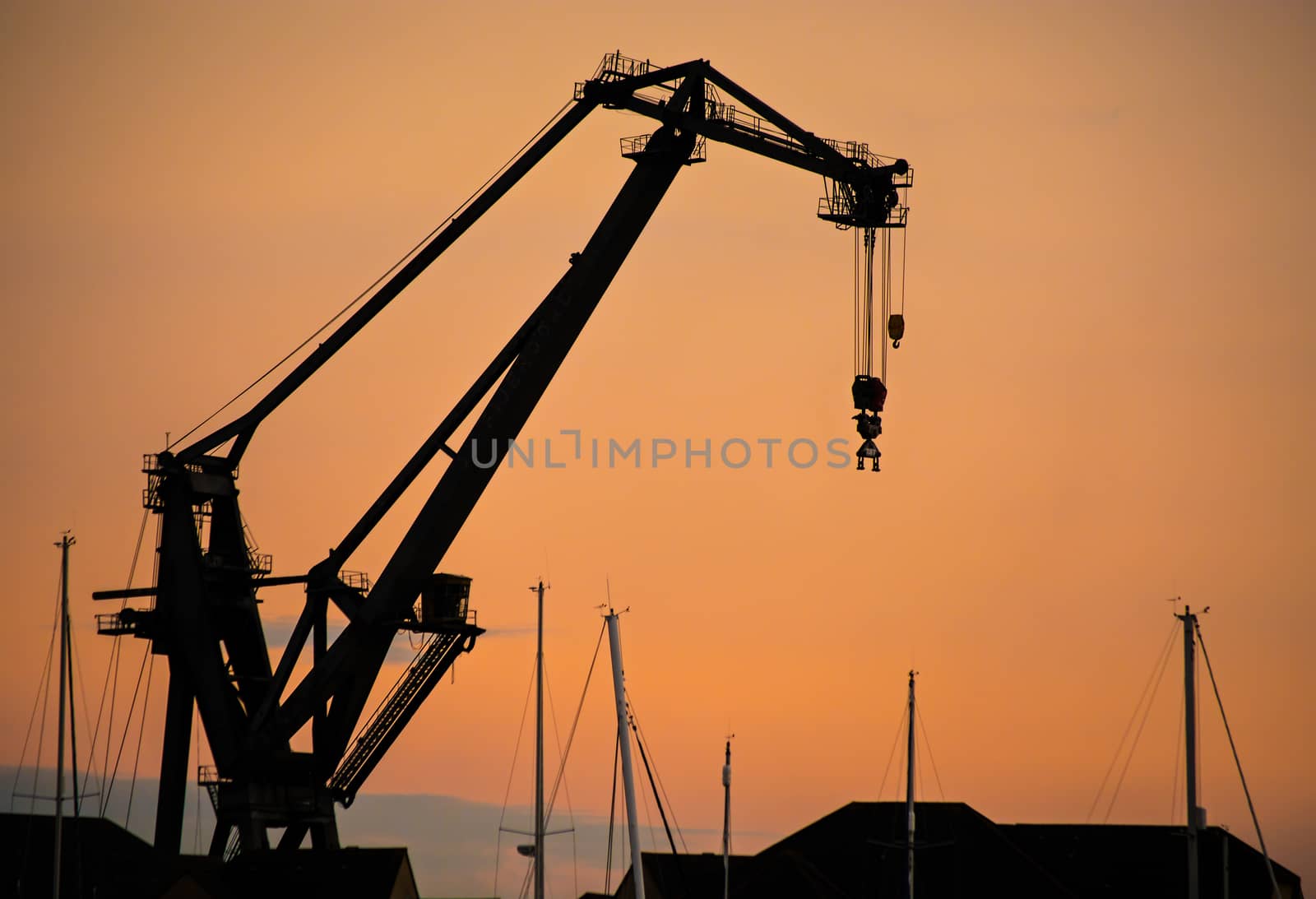 A dockside crane, silhouetted against the setting sun