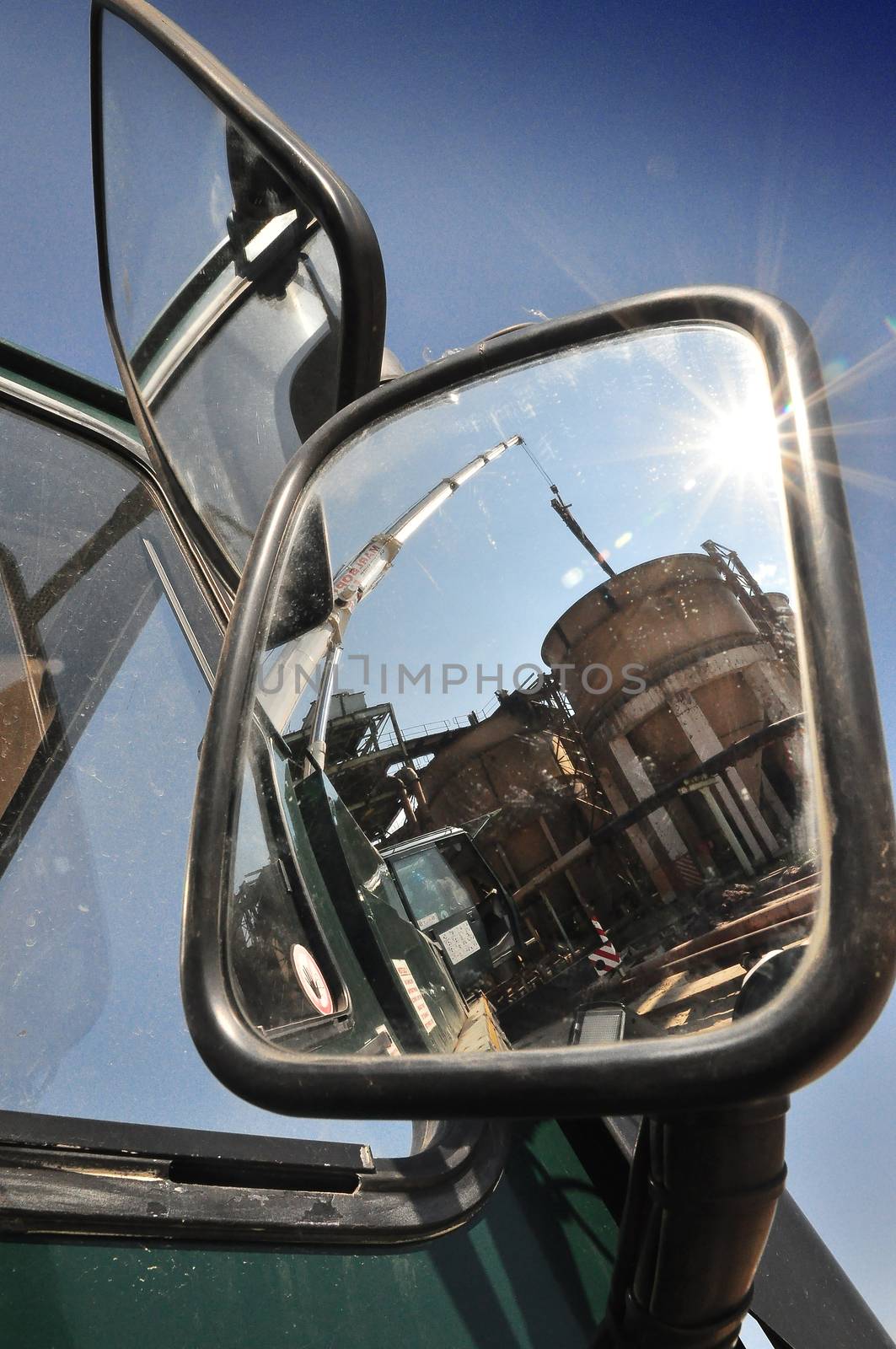 The actions of the truck-mounted crane can be seen reflected in its large exterior mirror.