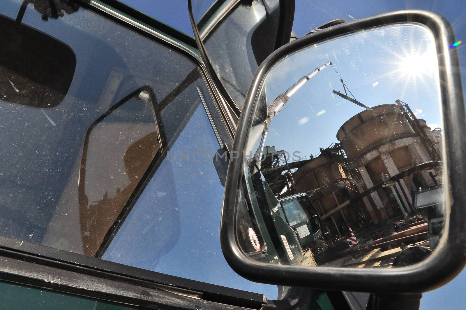 The actions of the truck-mounted crane can be seen reflected in its large exterior mirror.