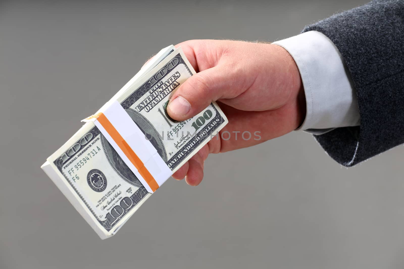 male hand holding a wad of hundred dollar bills by alexkosev