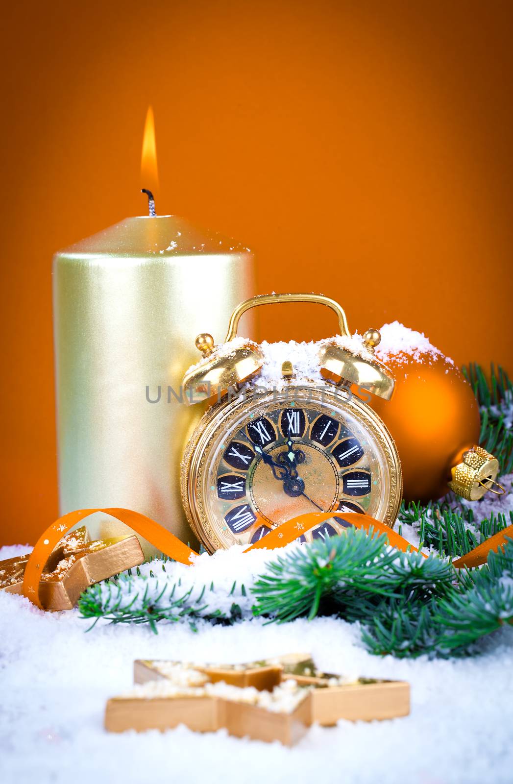 Christmas decorations - clock for the new year, candle, pine branch on orange background