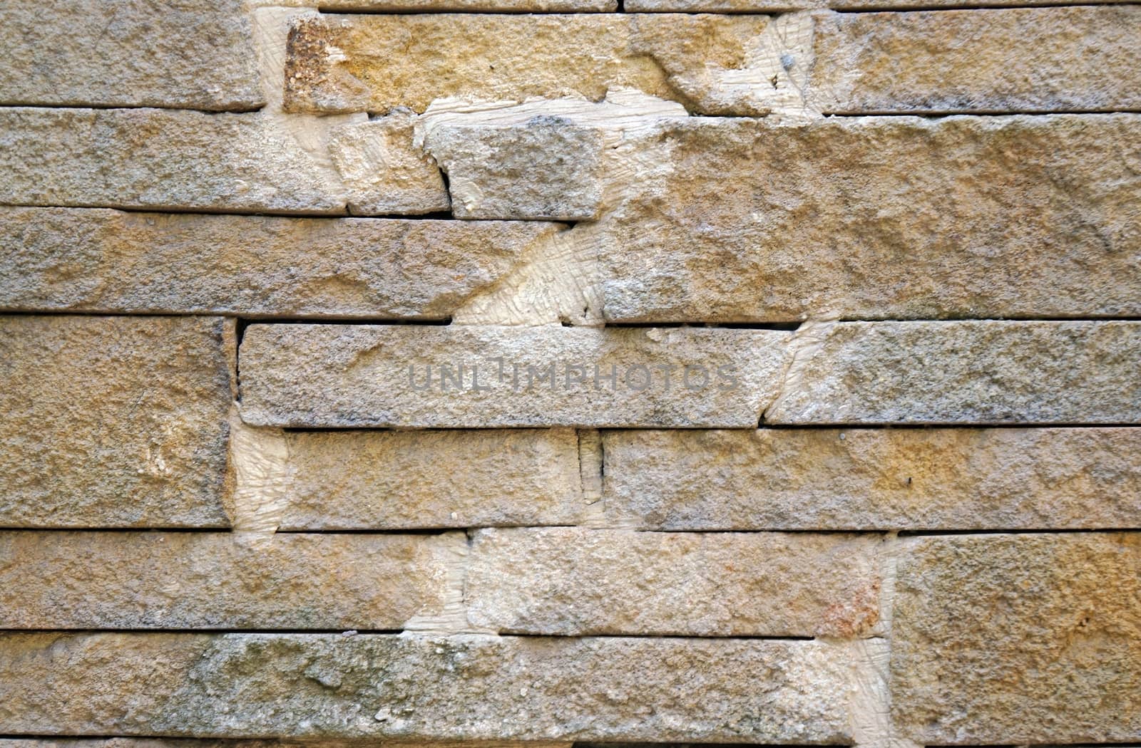 A fence made of beige stones fastened by cement as background