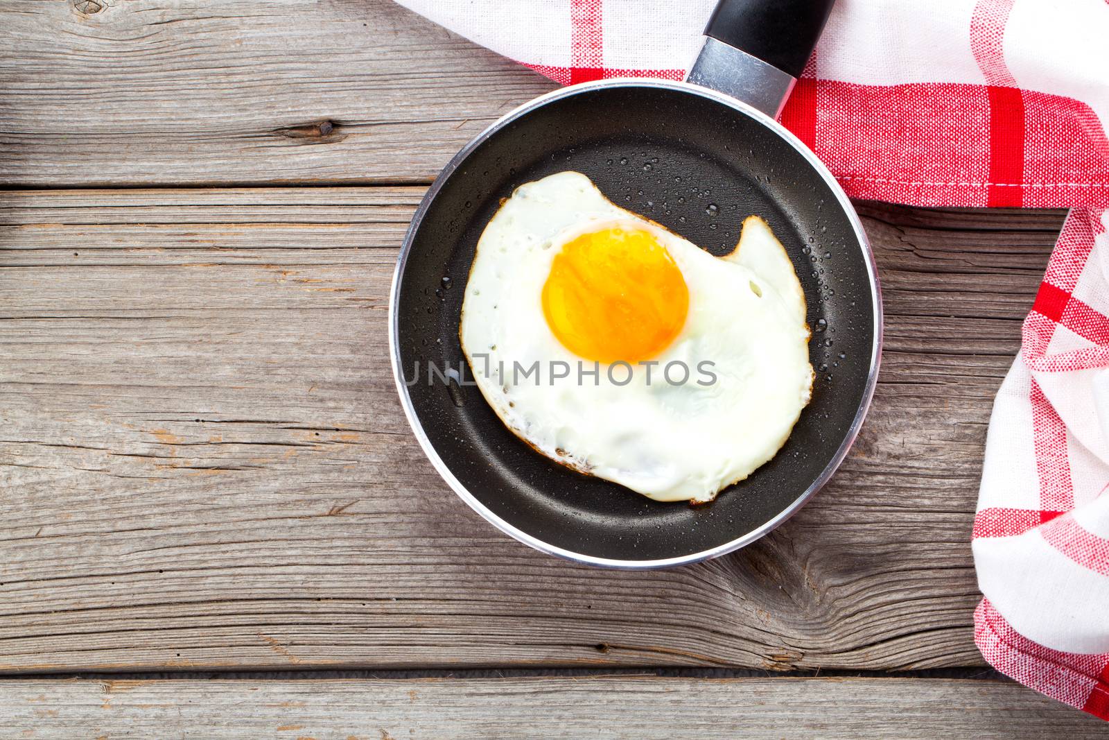Fried egg in a frying pan, on an old wooden table