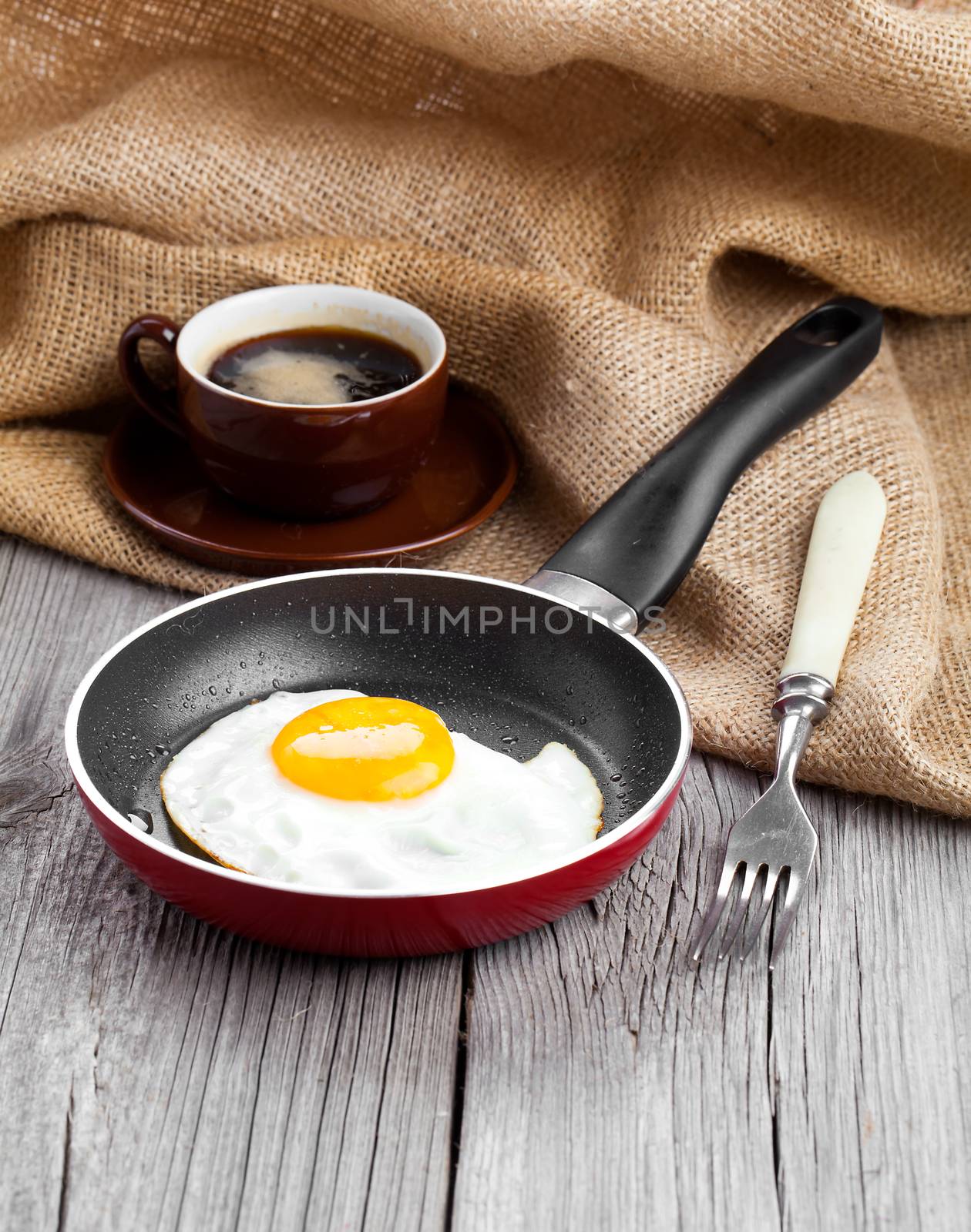 Fried egg in a frying pan, on an old wooden table