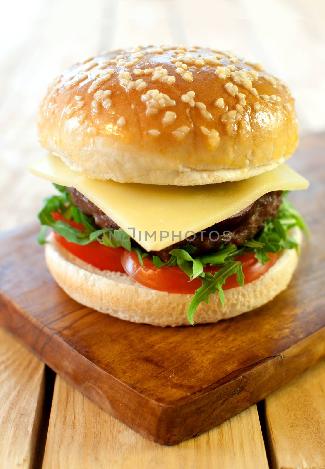 Hamburger with cheese and tomato filling on a cutting board