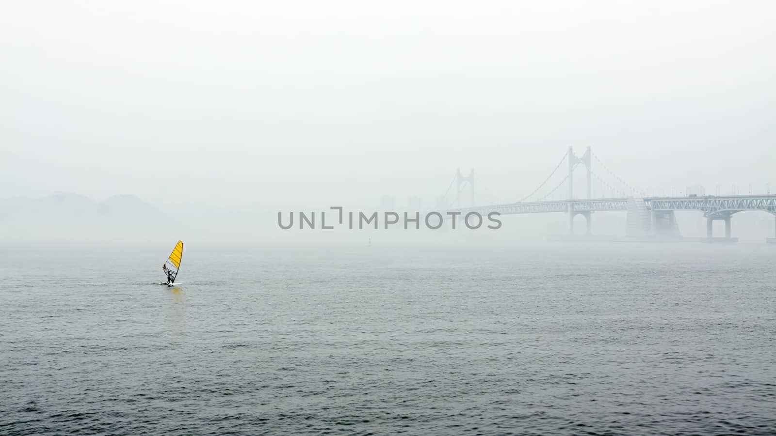 Misty landscape with river, bridge and yellow sail