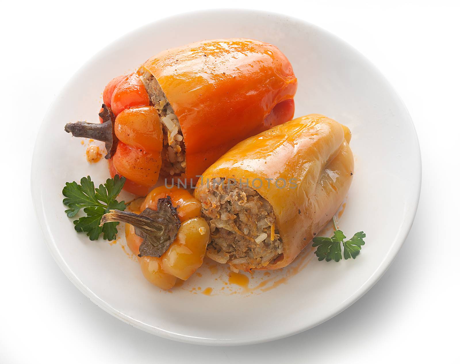 Two stuffed peppers with fresh parsley on the white plate