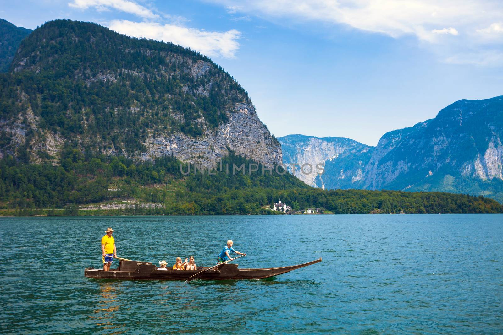 Hallstatt, Austria - August 7, 2013: People crossing the lake with a traditional boat typical for Hallstatt village, Austria