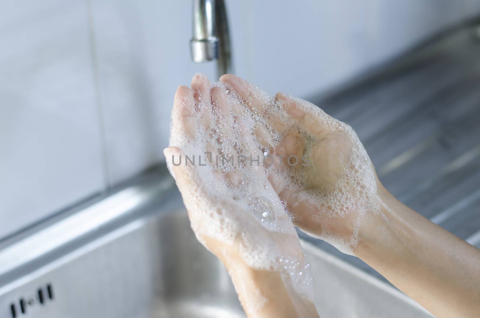 Washing of hands with soap on sink
