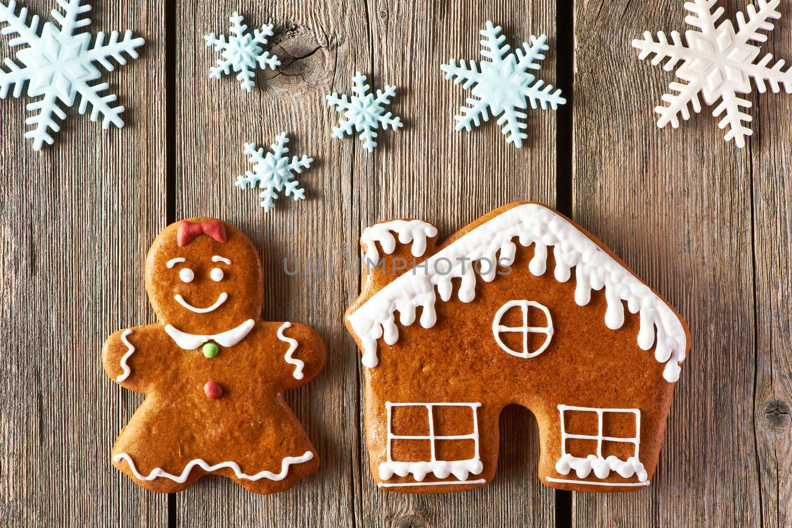 Christmas homemade gingerbread girl and house on wooden table