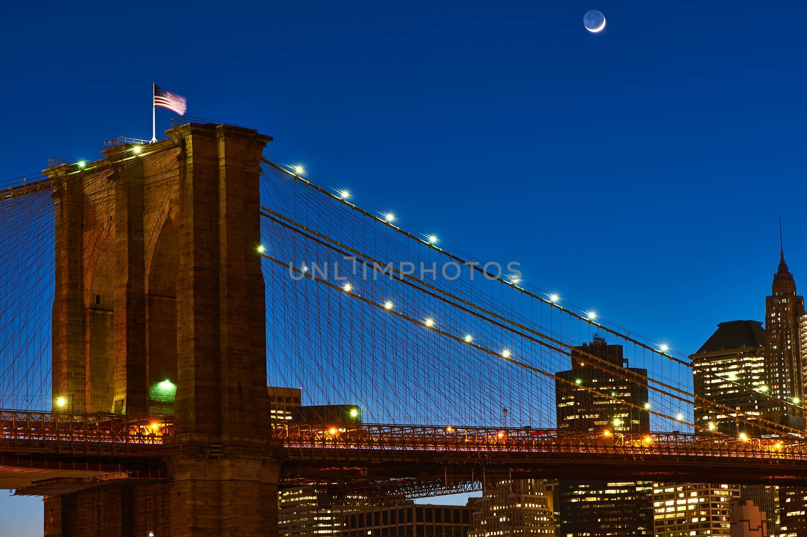 Close up of a pillar of the Brooklyn bridge with flag at night by haveseen