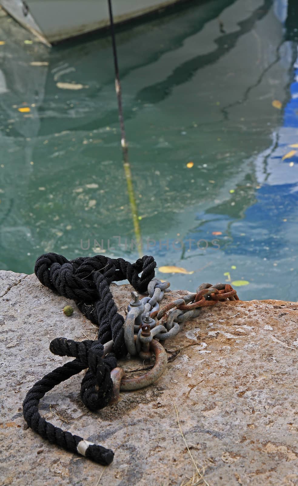 A close up of ropes and chains used to moor a boat in a harbour