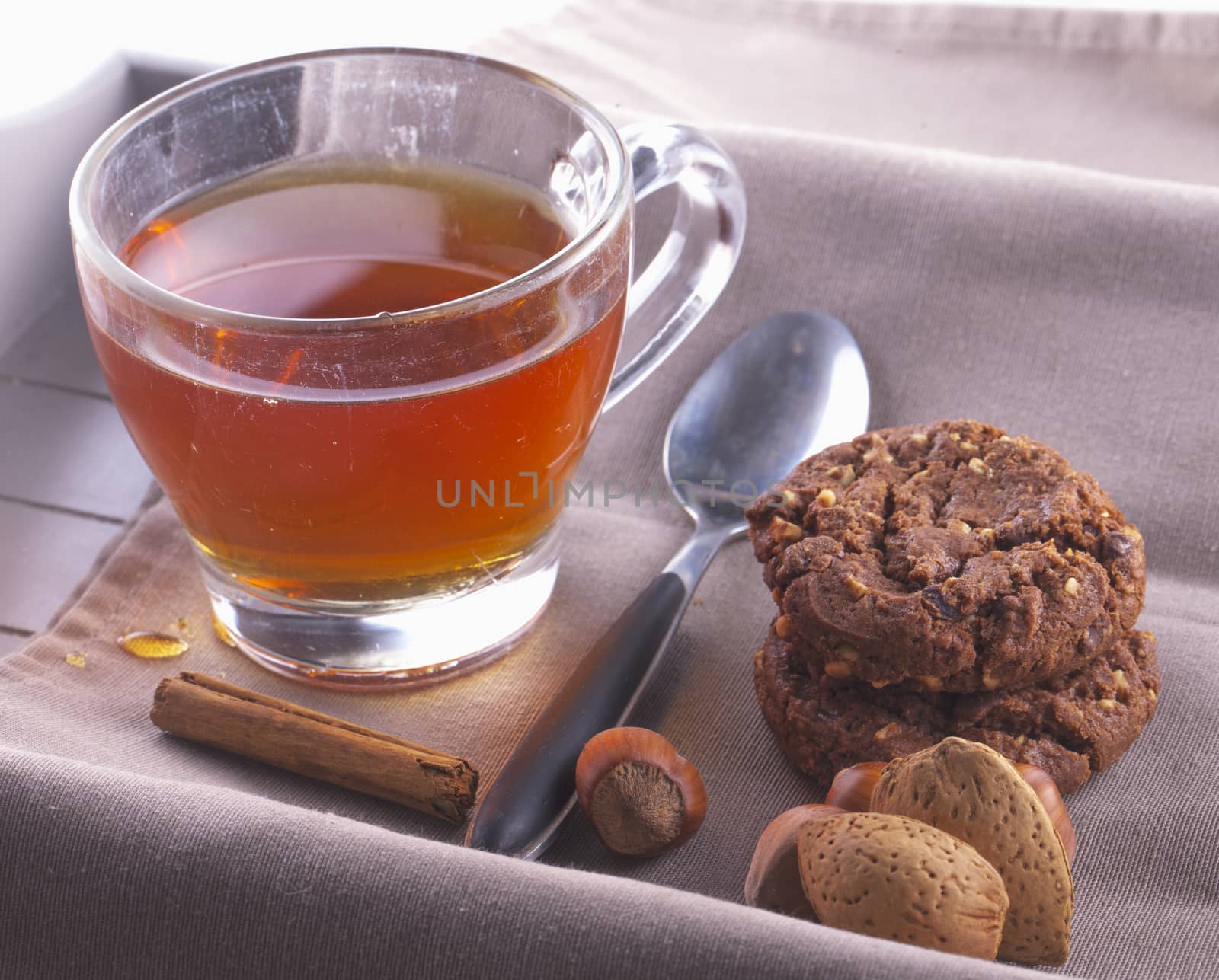 Tea with biscuits, nuts and cinnamon over tray