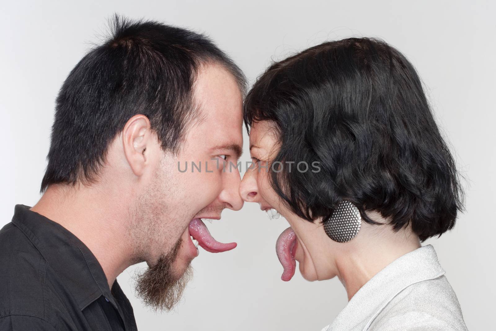 couple sticking out their tongues at each other - isolated on white