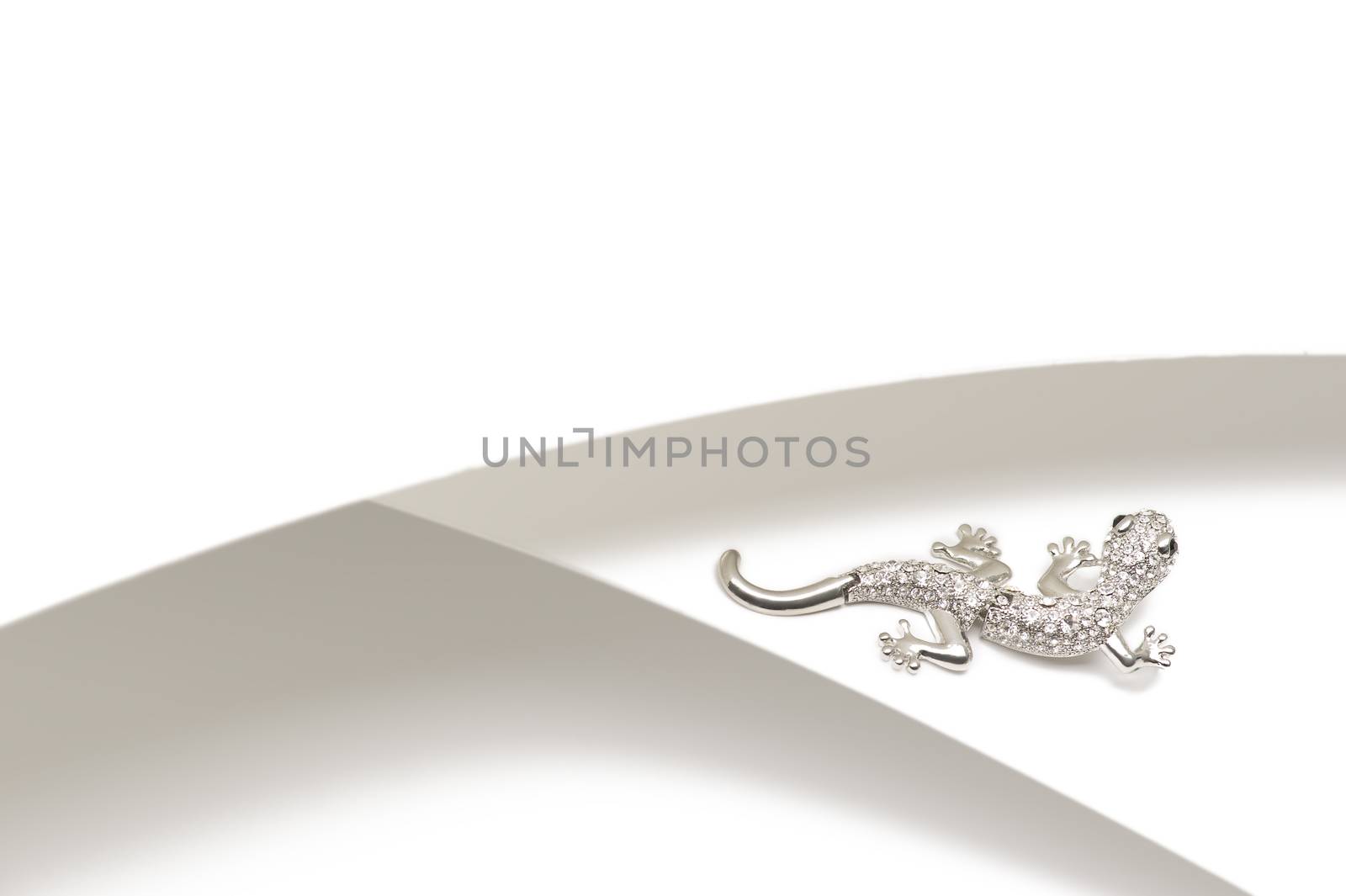 Silver gemstone lizard brooch set with shiny cubic zirconias or diamante for a chic fashion accessory on a bicolor silver and white background with copyspace