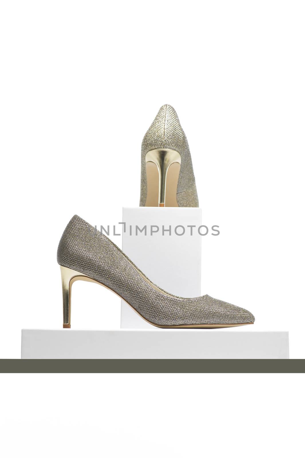 Pair of elegant classic high heeled silver ladies court shoes for evening wear on display in side view and viewed from behind on pedestals, isolated on white