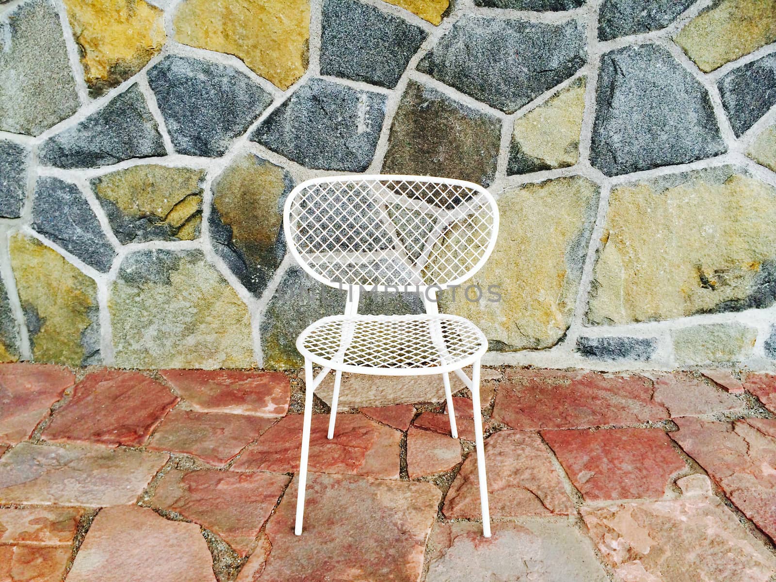 White mesh chair on colorful tile background, outdoors.