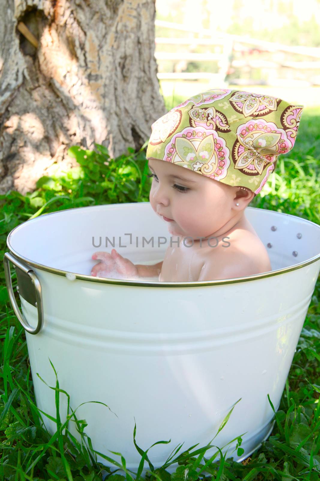 Beautiful baby girl having a bath outdoors 