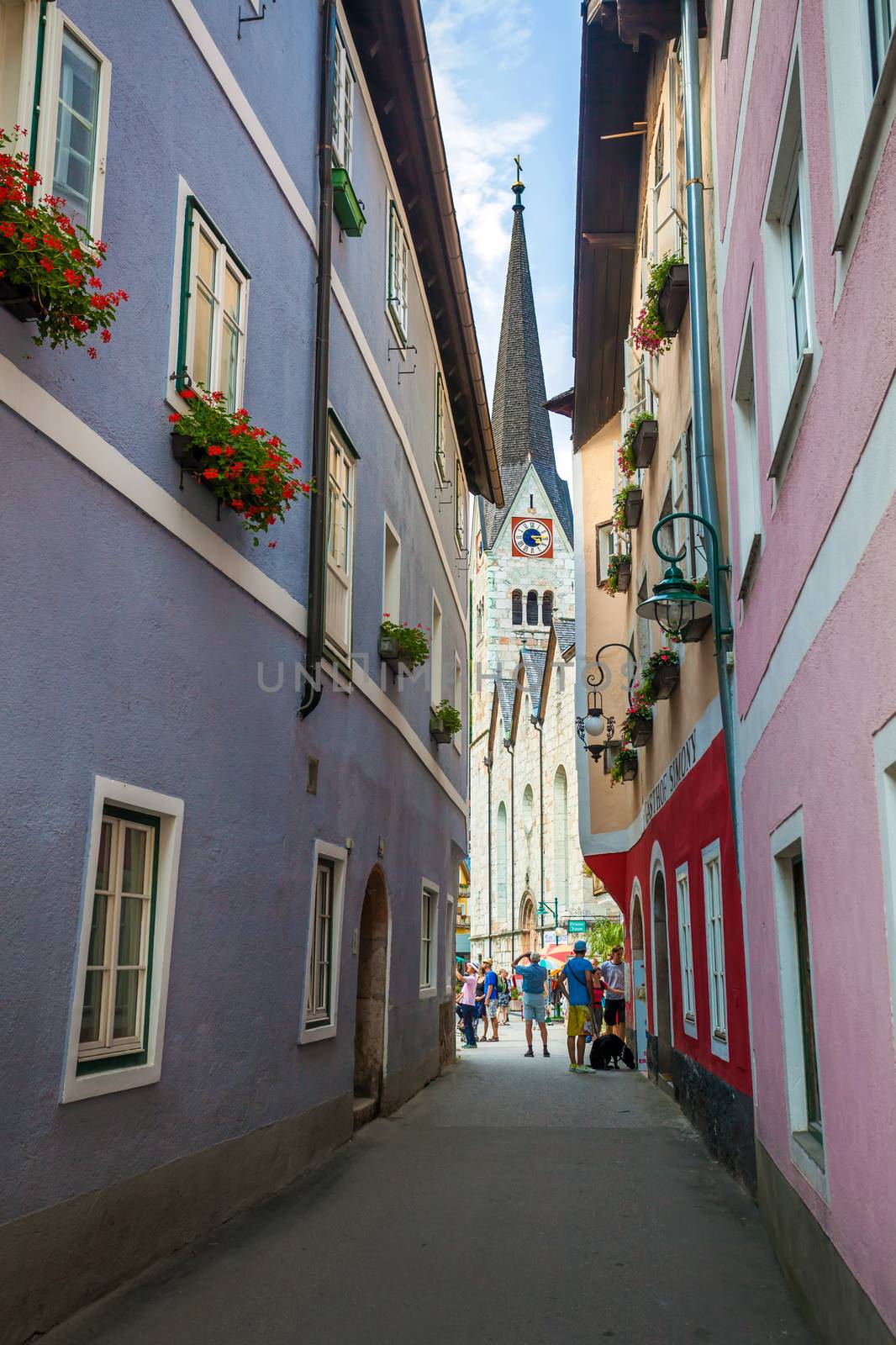Hallstatt, Austria - August 7, 2013: Typical street with tourists in front of the Halstatt village church, Halstatt, Austria