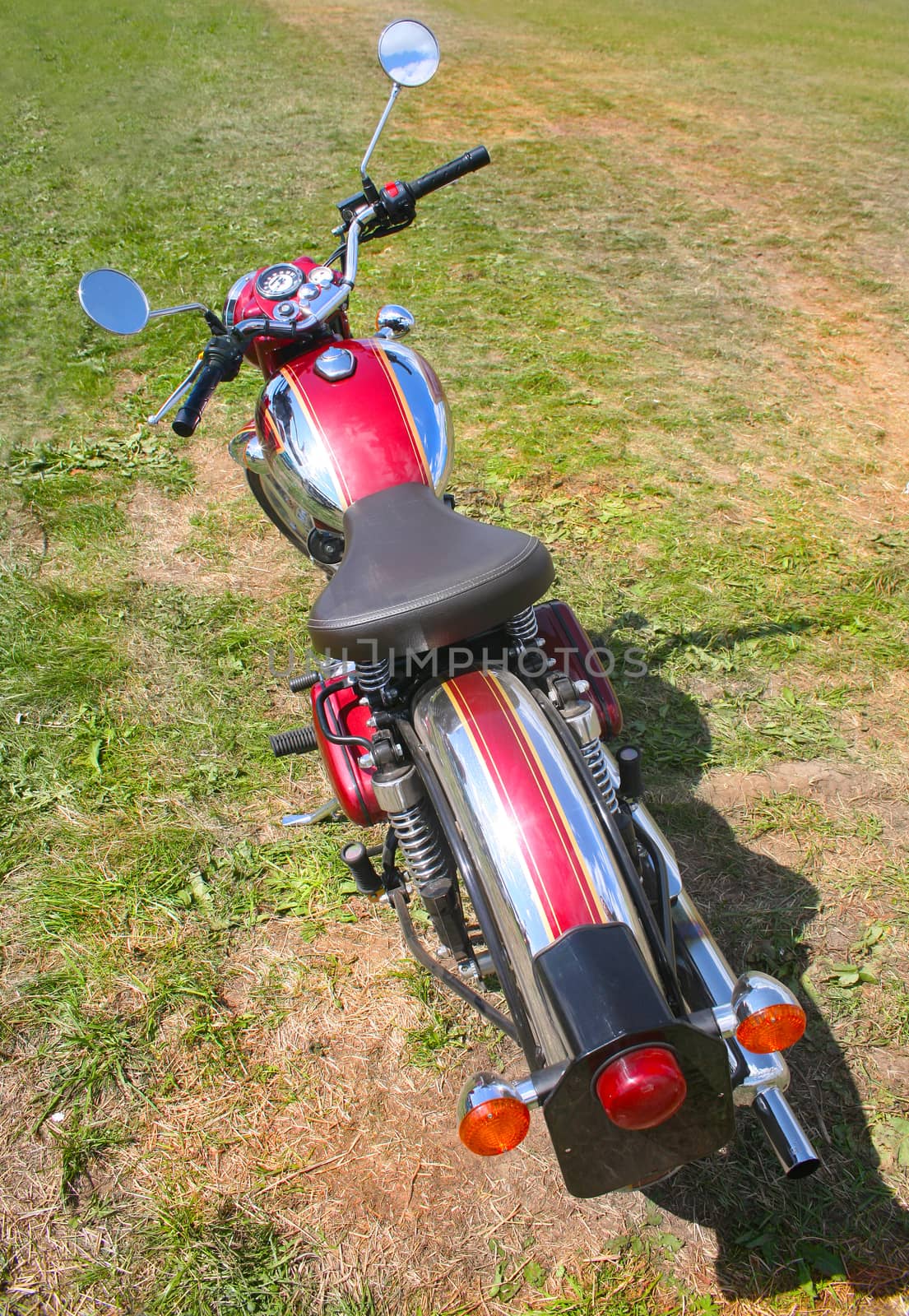 red motorcycle on meadow overgrown with grass
