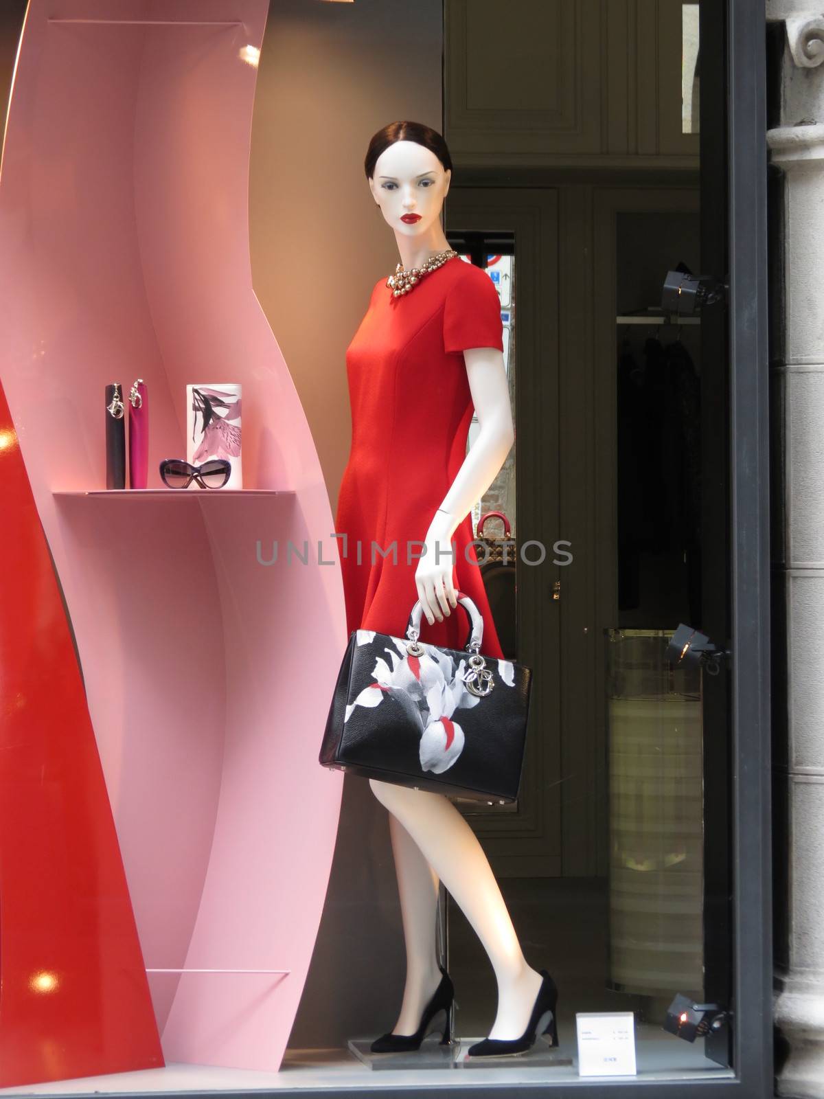 MILAN (ITALY), 31 JULY 2014 - woman mannequin with stylish red dress and black bag in a shop-window