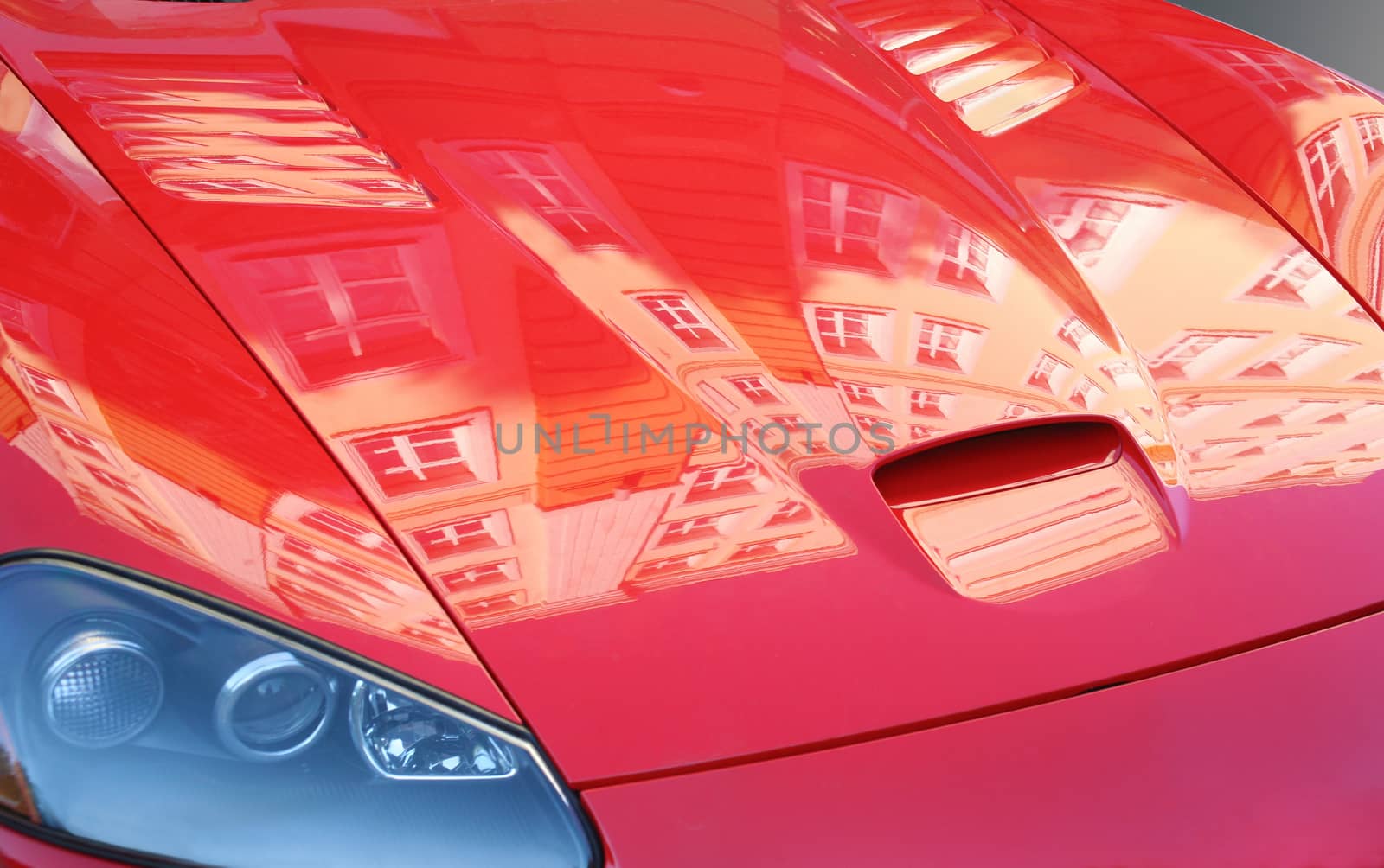 Cowl of  red sports car with building reflexion