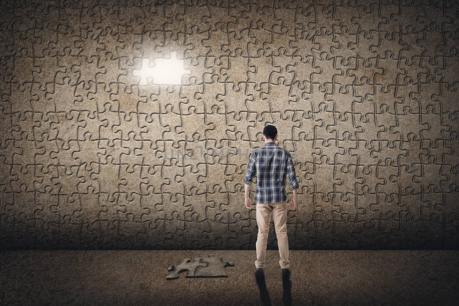 Asian man standing in front of a puzzle wall. Concept of mystery, problem, solution.