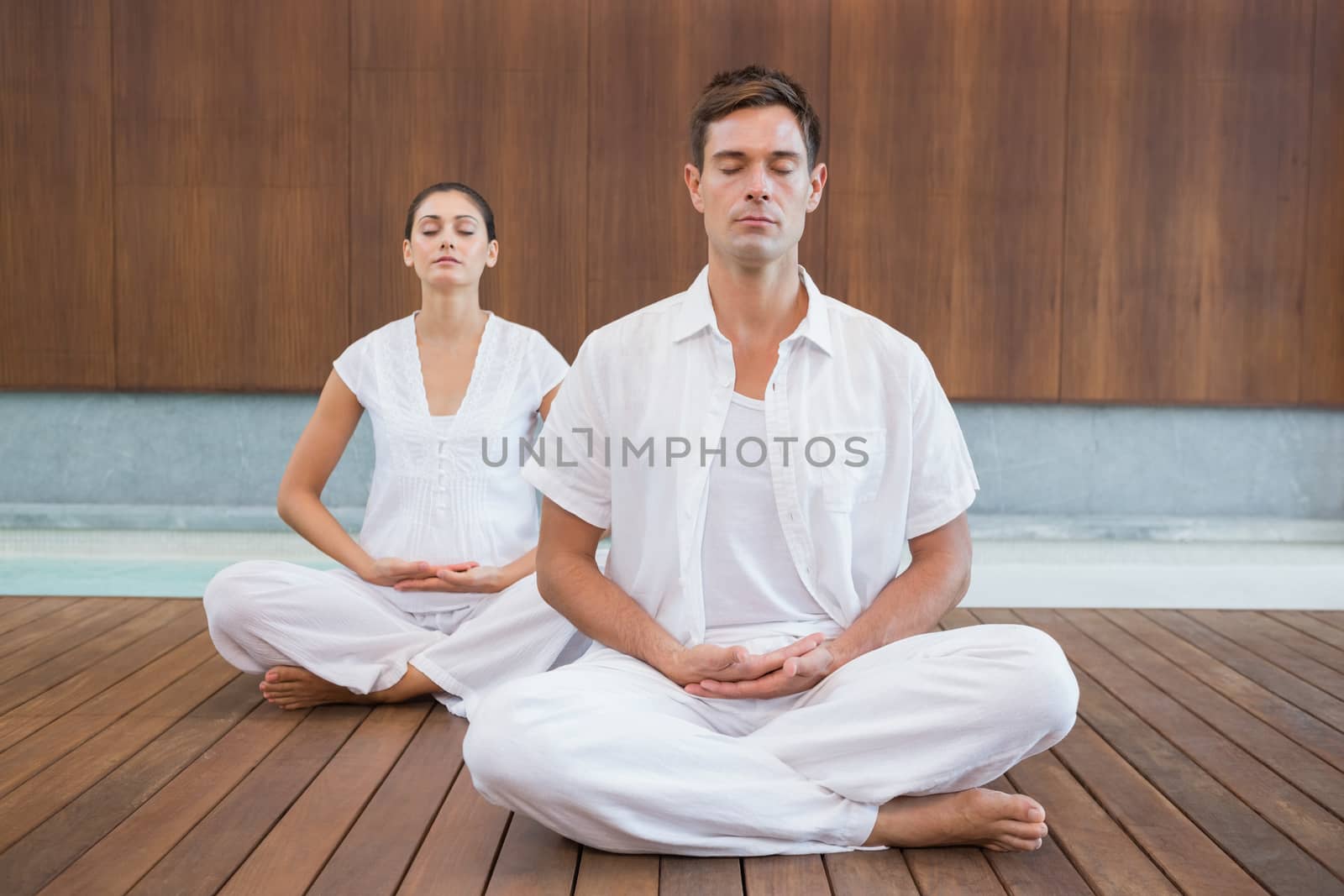 Peaceful couple in white sitting in lotus pose together by Wavebreakmedia