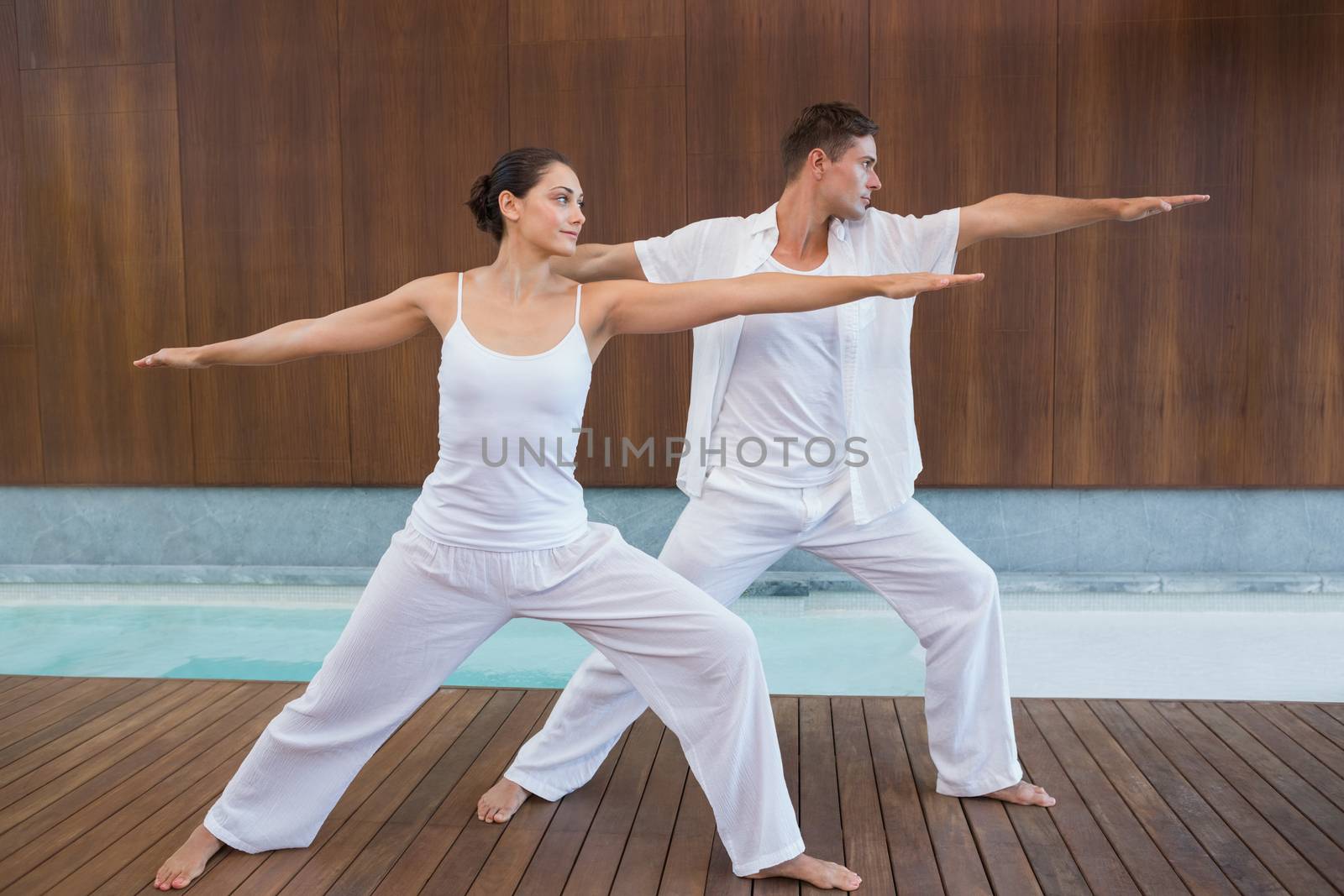 Peaceful couple in white doing yoga together in warrior position by Wavebreakmedia