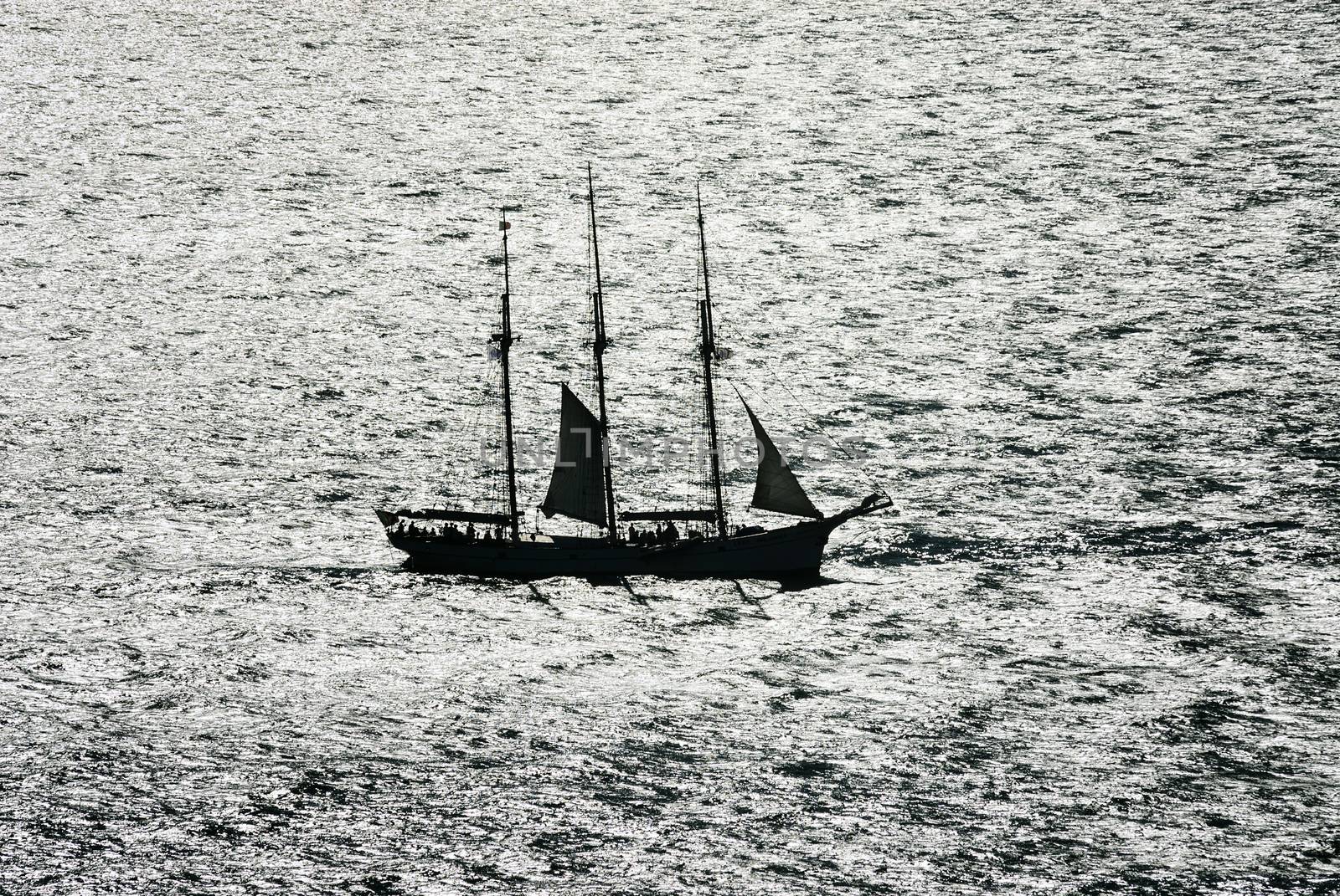 Sail boat gliding in open sea at sunset 