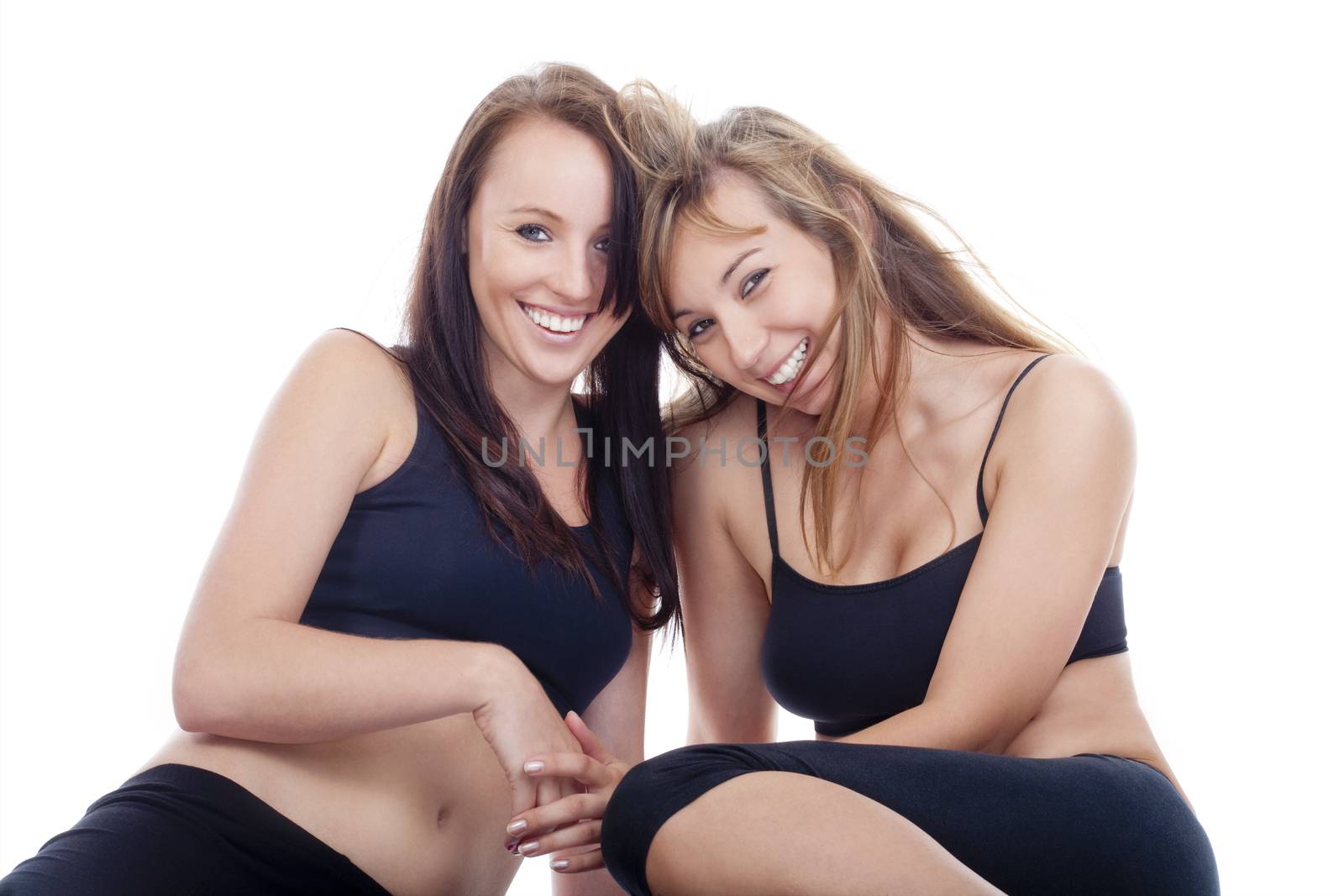 two young women in sport clothing smiling - isolated on white