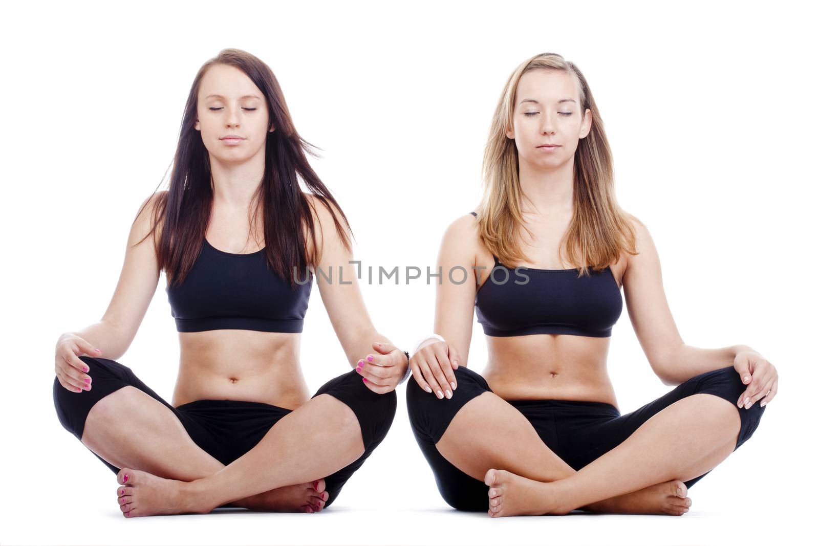 two young women sitting on the floor exercisng yoga - isolated on white