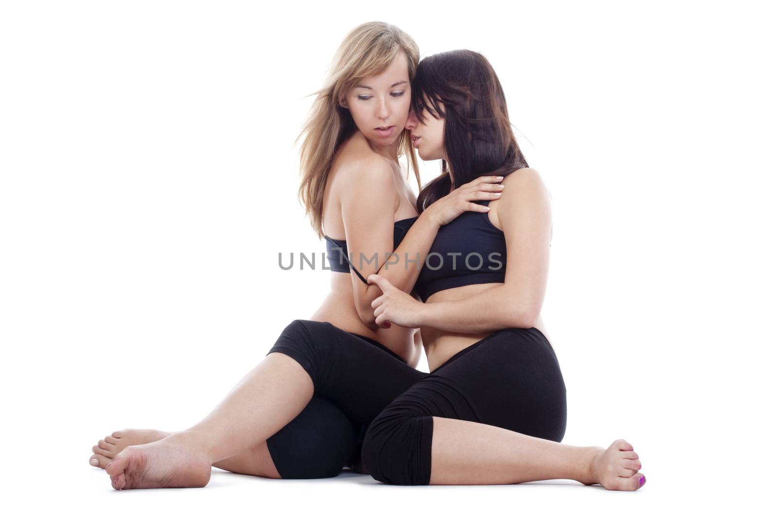 two young women sitting on the floor touching each other - isolated on white