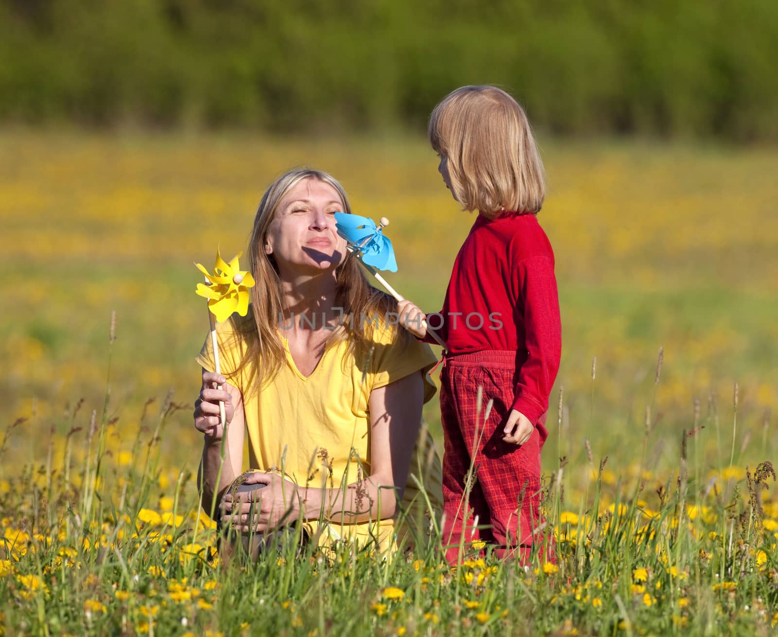 mother and son playing with pinwheels in a dandelion field