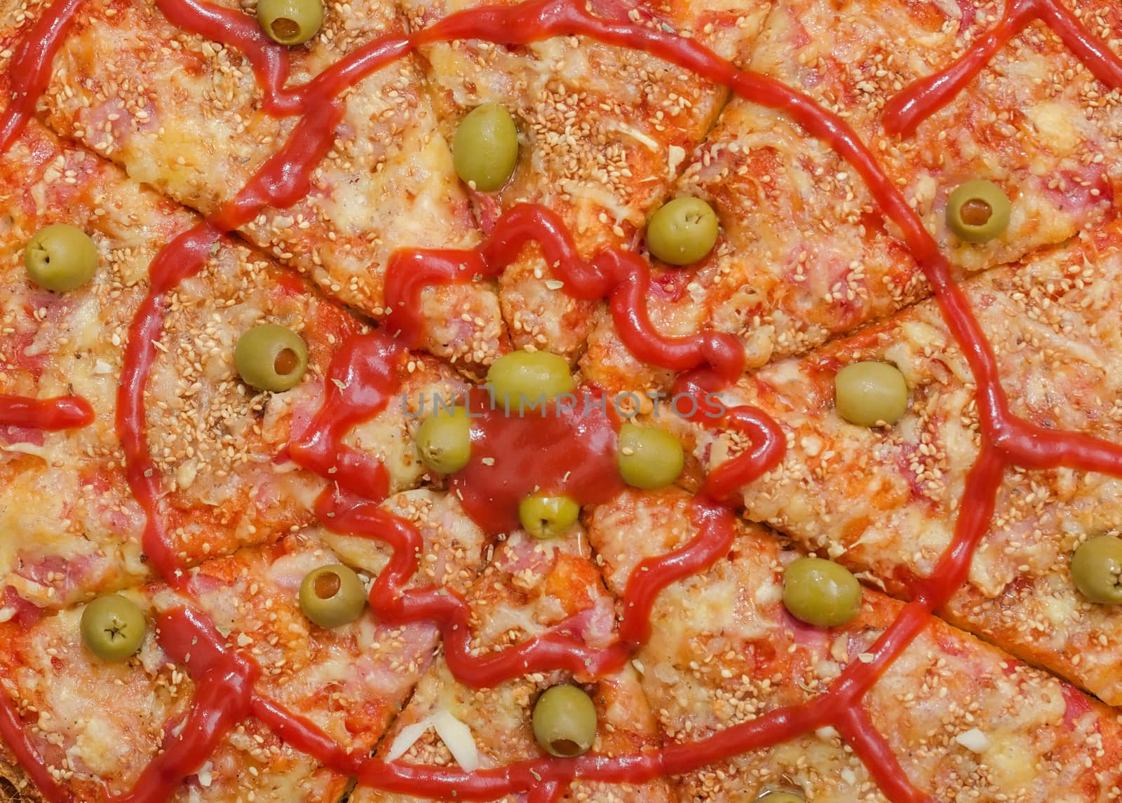 Background of Sliced Pizza with Ham, Bacon, Cheese, Green Olives filled with Paprika, Sesame , Garlic and Tomato Sauce, Closeup shot from above