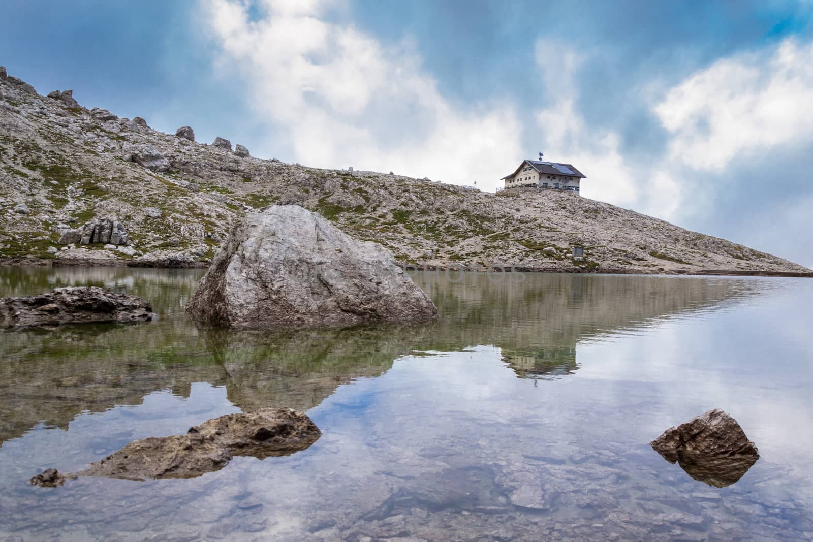 Italian Alps in Val Badia, Reflection of a mountain shelter in a lake