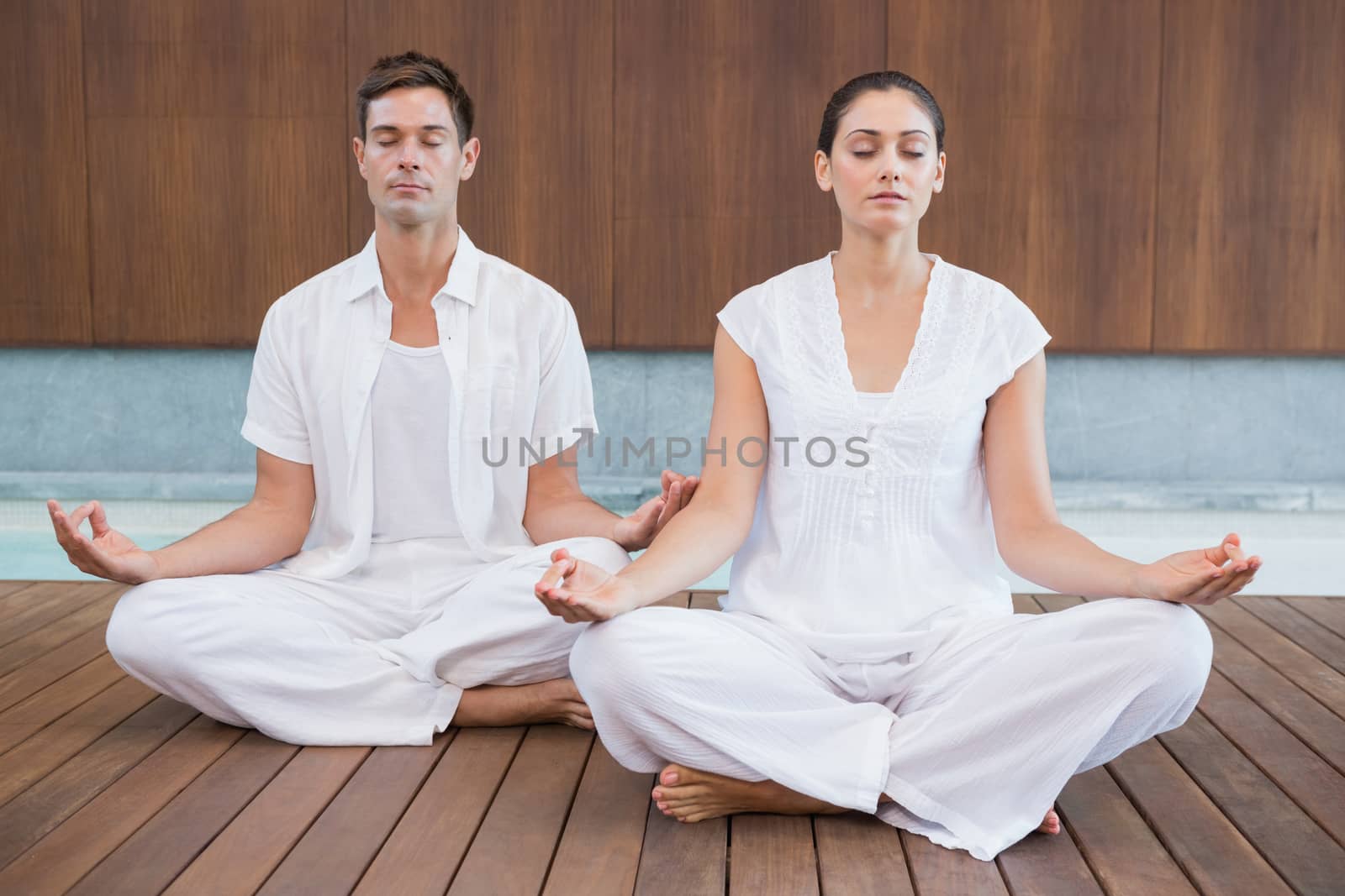 Attractive couple in white meditating in lotus pose by Wavebreakmedia