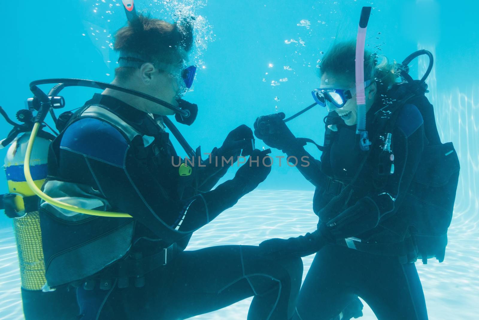 Man proposing marriage to his shocked girlfriend underwater in scuba gear  on their holidays