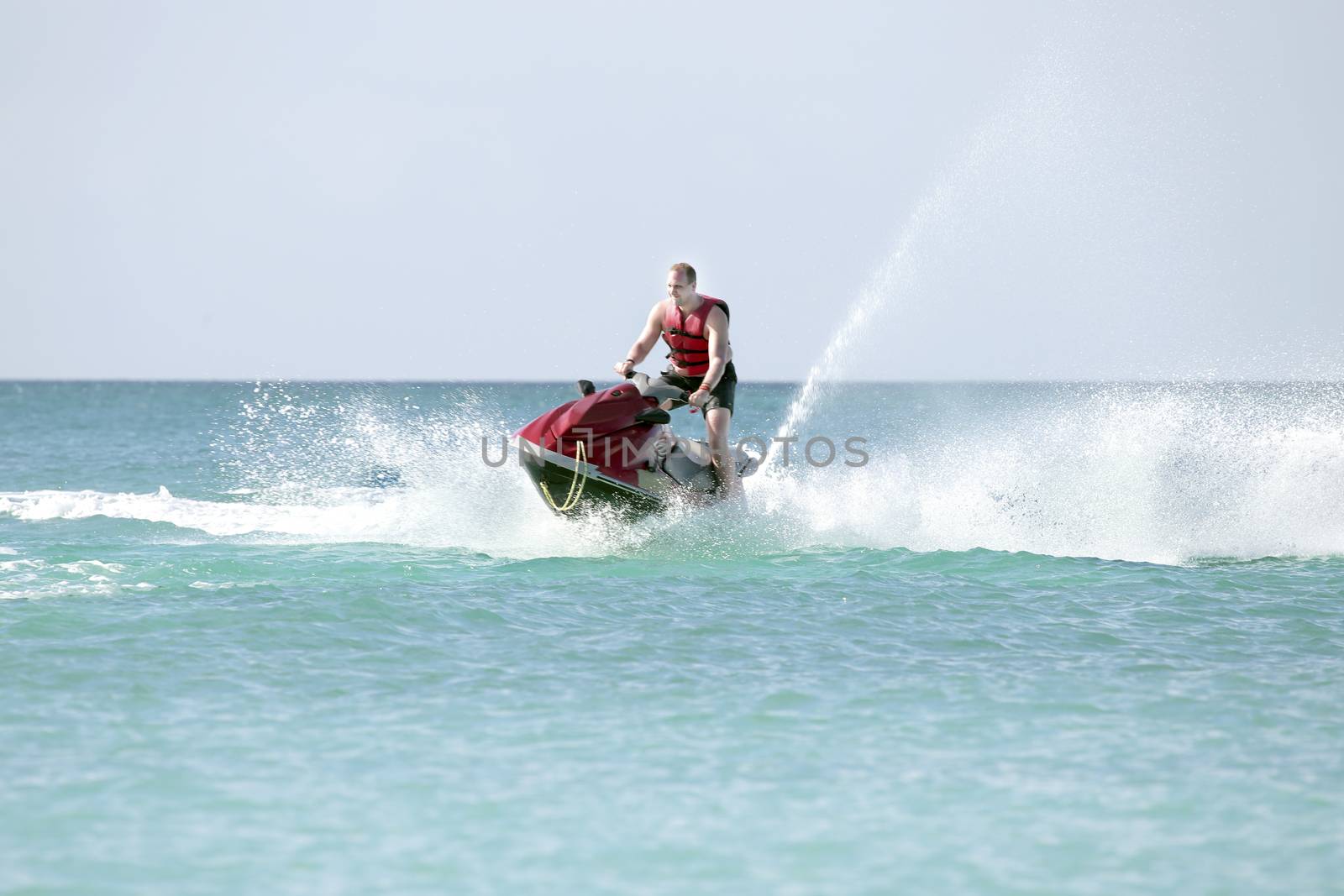 Young guy cruising on the caribbean sea on a jet ski by devy